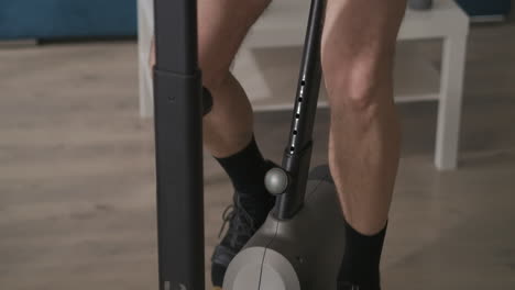 middle-aged-man-on-exercise-bike-at-home-closeup-shot-from-feet-to-face-during-workout-healthy-lifestyle-and-sport-activities